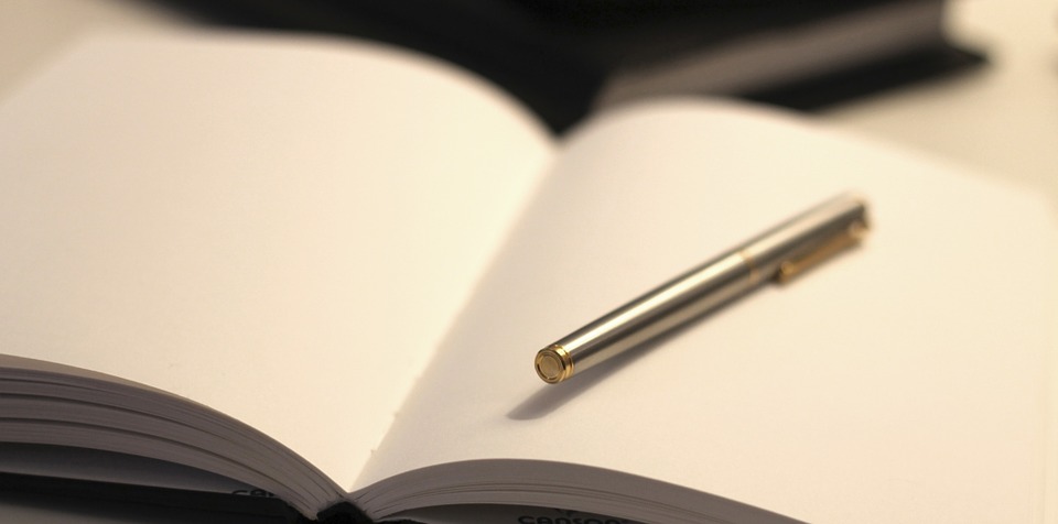 A silver pen in a blank, open journal.