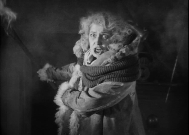 Gerda Lundqvist as Fru Samzelius in the silent movie adaptation of Gösta Berling's Saga. Distraught and disheveled, dressed in piecemeal fur rags, she carries a torch, ready to burn her own home to the ground rather than hand it over to her enemies.