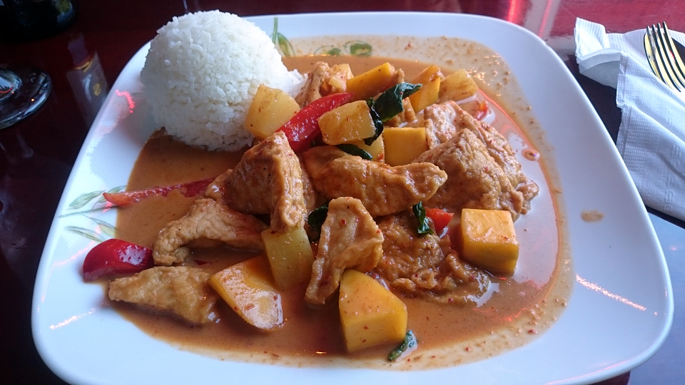 A delicious-looking Thai red curry on a funky square white plate.