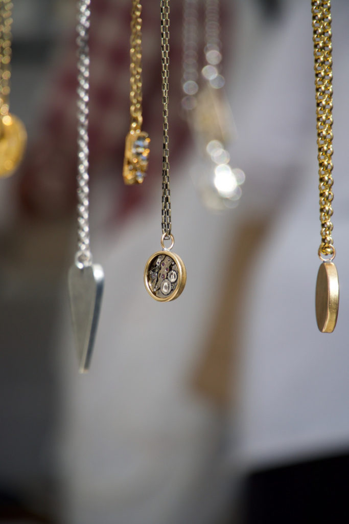 Gold and silver Victorian fascinators and lockets suspended from an unseen hand or display.