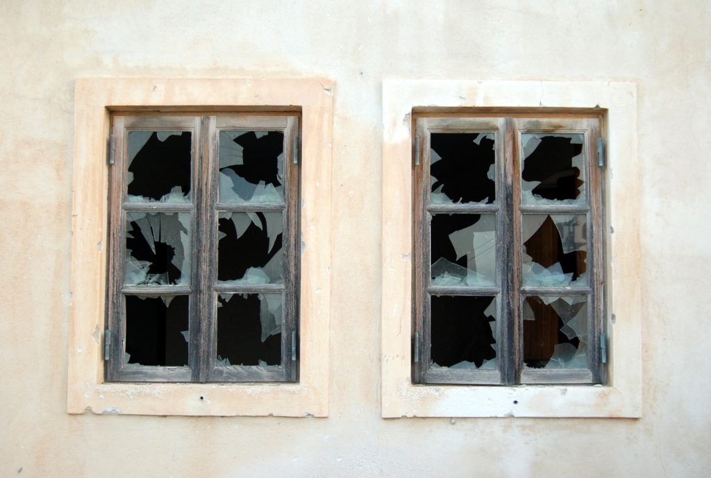 A pair of broken windows in a white wall.