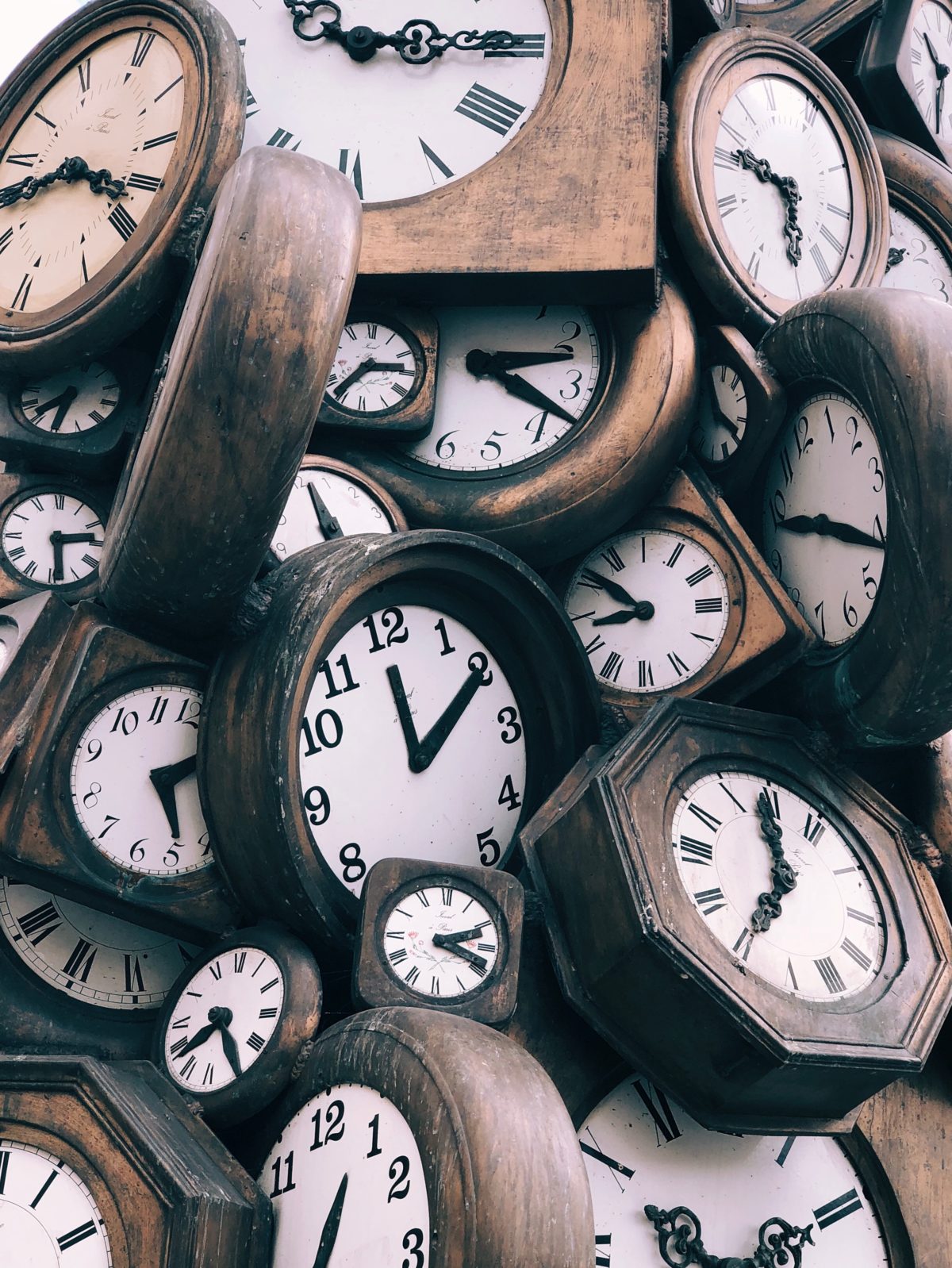 Lots of different wooden clocks, all set at different times, jumbled in a pile.