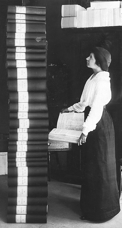 Elin Wägner in front of the 351,454 signatures collected to support women's right to vote, a stack of binders half a meter taller than herself.