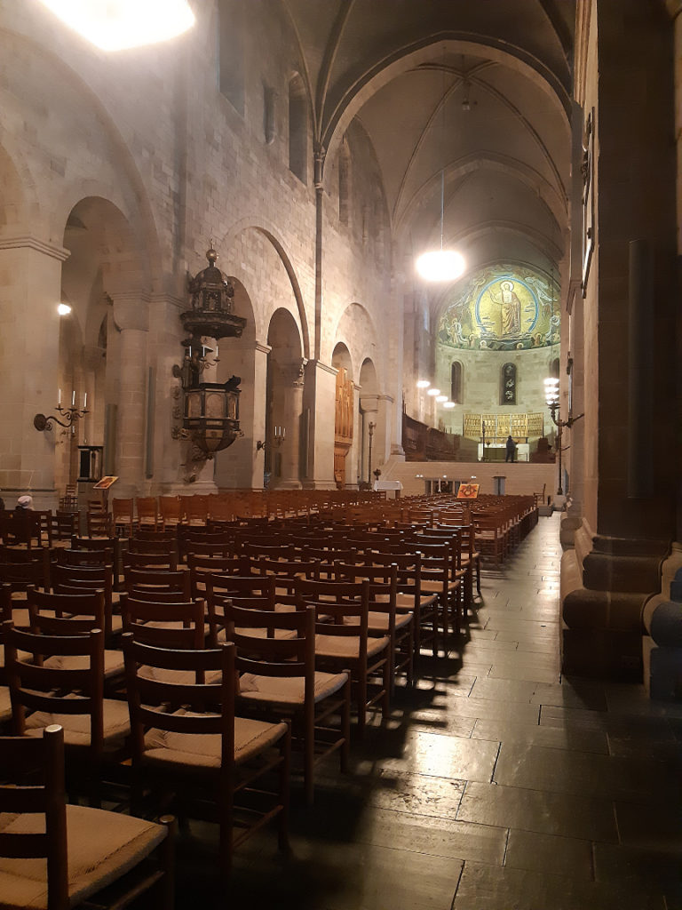 Interior of the Lund Cathedral, facing the altar behind rows of wooden chairs.