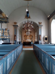 The interior of Frösö chuch, facing the altar. A copper chandelier hangs from the ceiling, and the interior is decorated in a blue and gold motif.